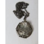An antique coin in a/f condition, mounted in hallmarked silver frame on unmarked white metal chain,