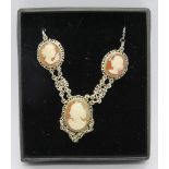 A delightful cameo necklace featuring three carved shell portraits in white metal filigree mounts.