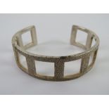 An HM silver bangle having open square shaped panelling, 38.9g.