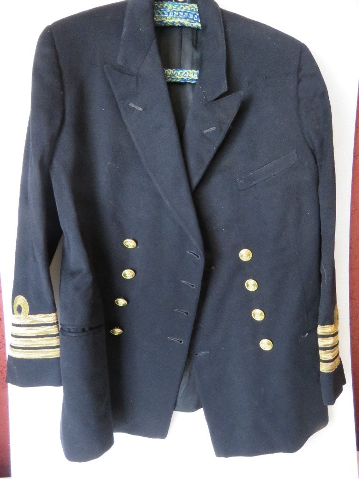 A British Naval jacket having brass buttons and four gilt stripes to cuff.