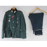 A reproduction German Combat Jacket with Insignia, and breeches.