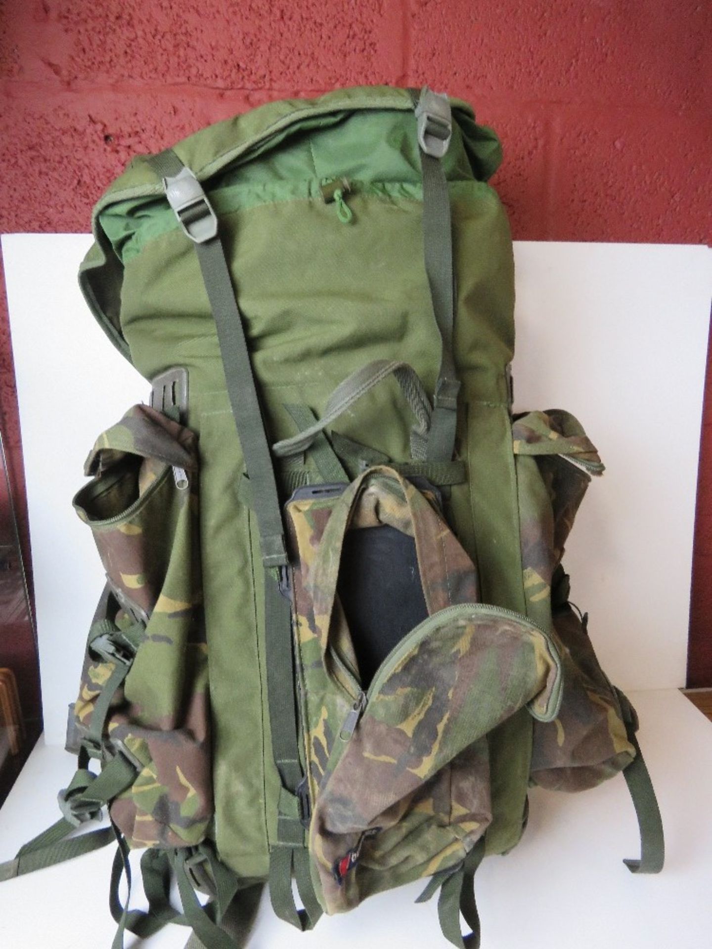A Berghaus camouflage military rucksack containing a large quantity of kit inc black leather boots,