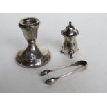 A hallmarked silver short candlestick together with HM silver pepperette, and HM silver sugar tongs.