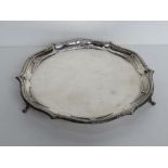 A hallmarked silver salver raised over three outswept feet,