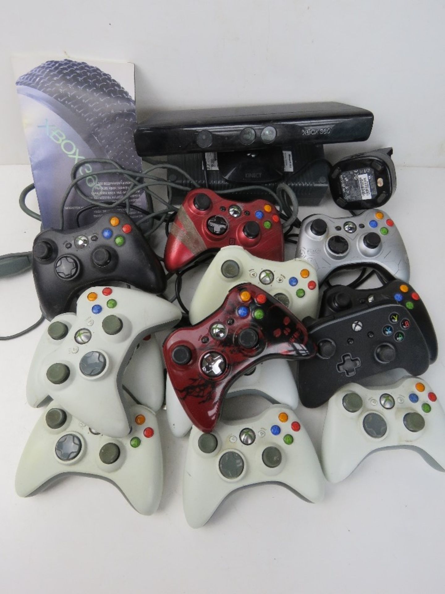 A quantity of XBox controllers, together with an instruction manual, charger and XBox 360 Kinect.