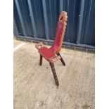 A carved wooden three legged high backed stool having leatherette seat.