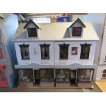 A delightful decorated and furnished dolls house in the form of two shops with homes over,