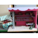 A dolls house market stall with flower cart and shelves stocked with woodworking and maintenance