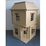 A two storey dolls house opening to reveal a toy shop with vast array of toys within,