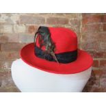 A 100% wool hat in red with feathers upo