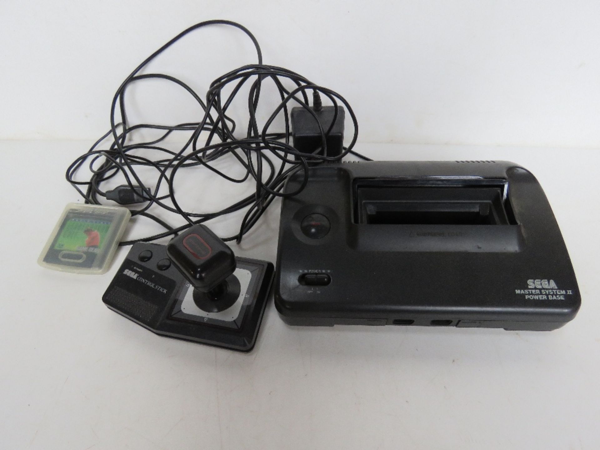 A Sega Master System II power base with game cartridge and controller.