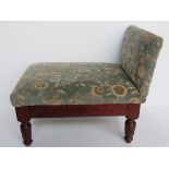An antique gout stool having green floral velvet upholstery.