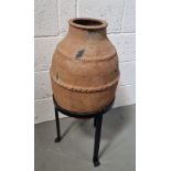 A decorative terracotta plant pot on wrought iron stand, approx 84cm high.