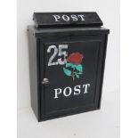 A black metal letter box with rose design to front with key.