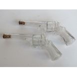 A pair of pressed glass whiskey flasks in the form of revolvers,