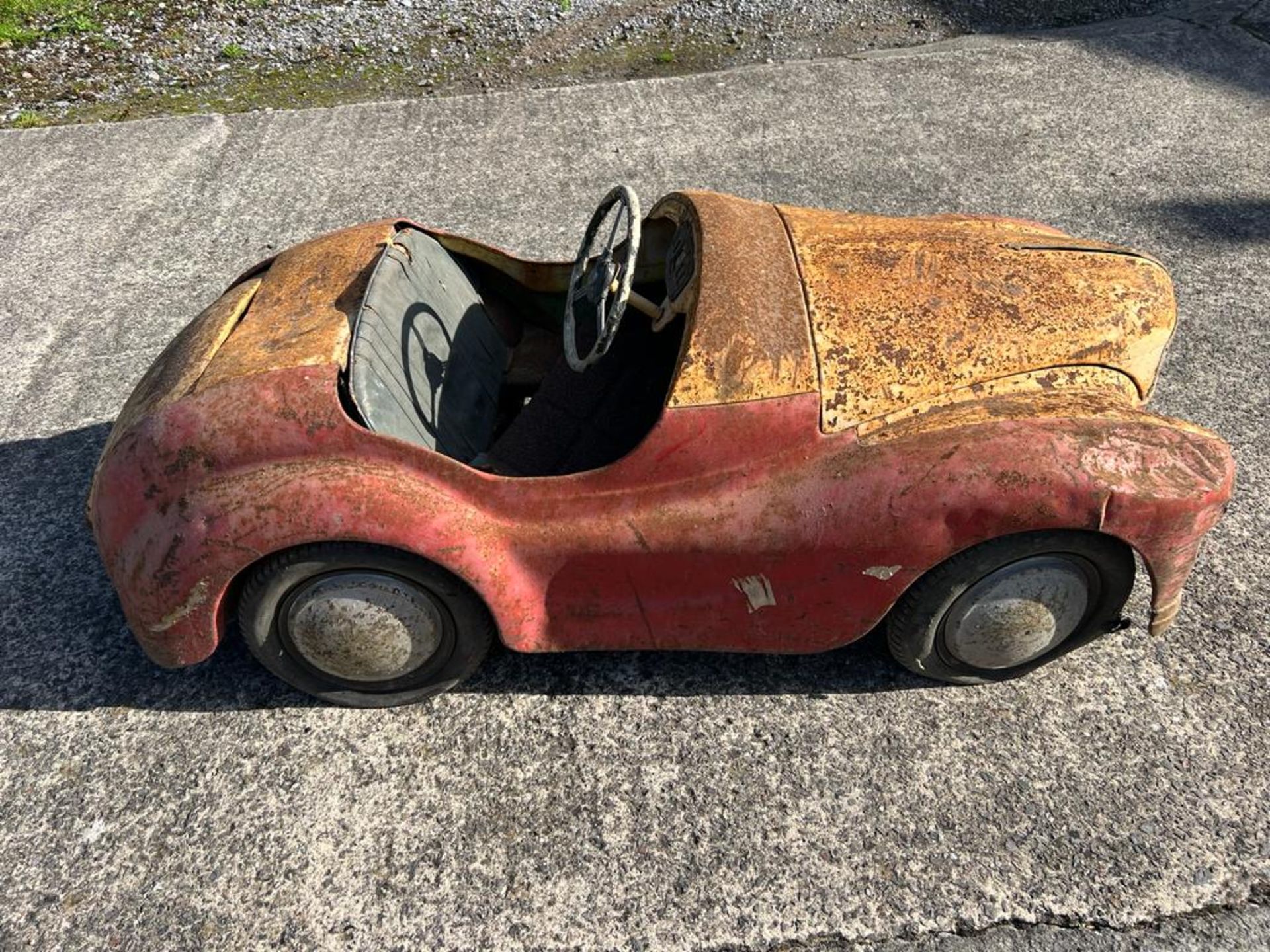 A vintage Austin J40 pedal car in barn find condition.