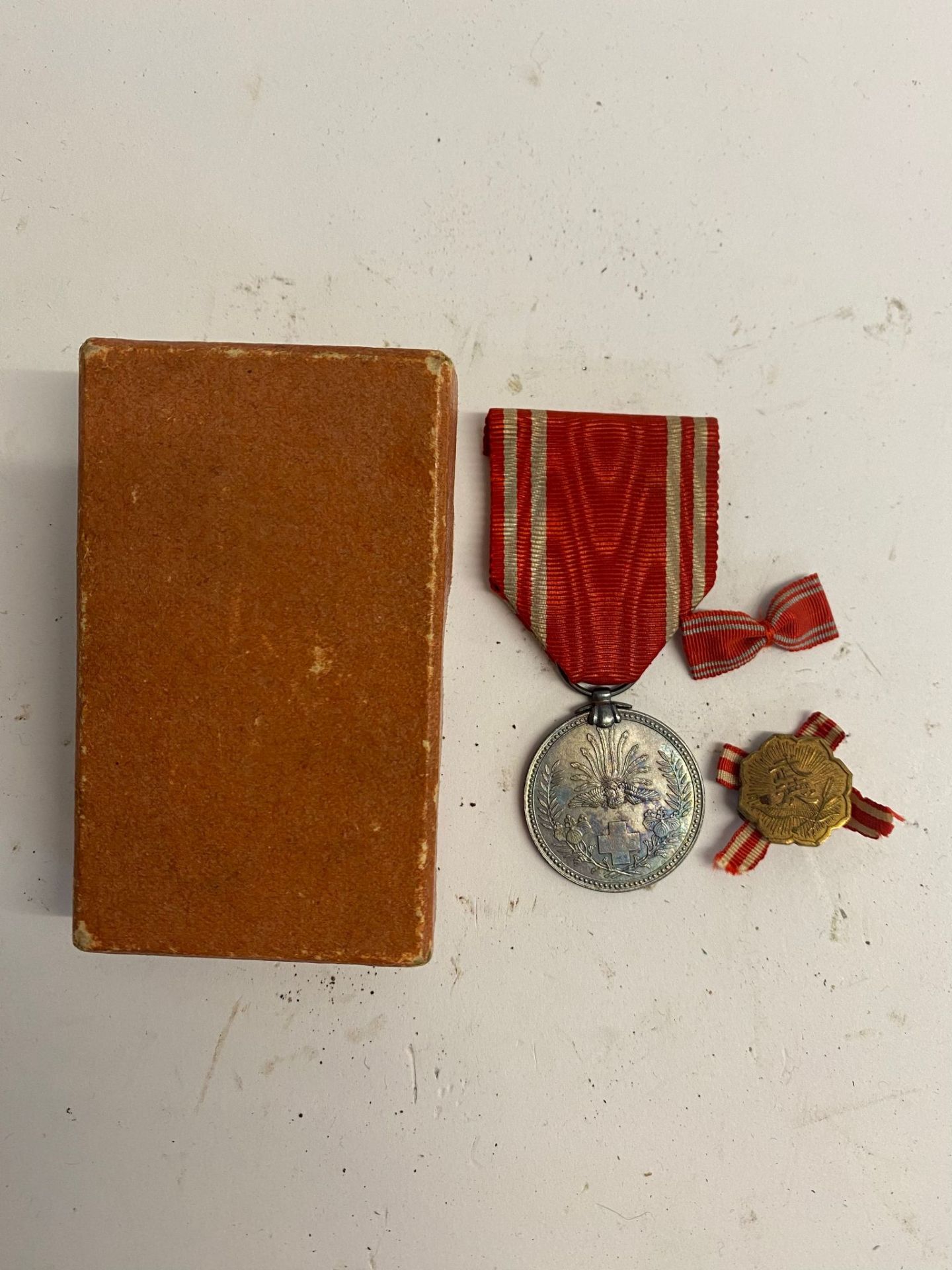 A WWII Japanese red cross medal and lapel badge in box. This lot will be available to collect in