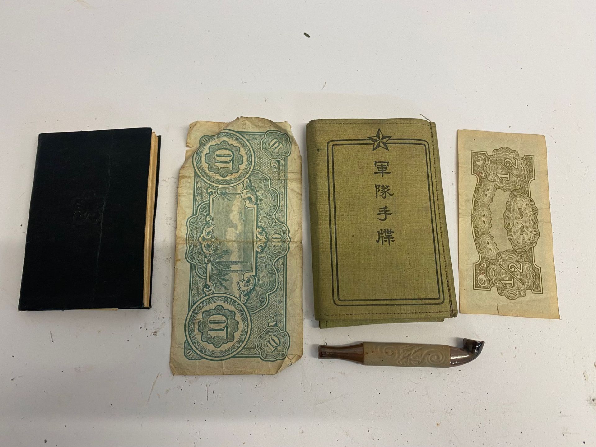 WWII Japanese books together with a pipe and paper money, one of the books being a technical manual.