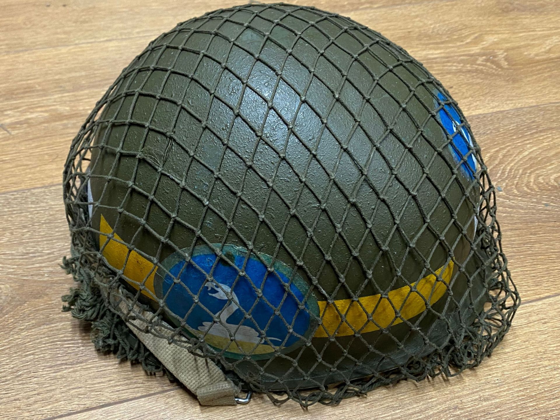 A US M1 military police helmet with a Vietnam era liner, modern decals, with netting and chin strap.