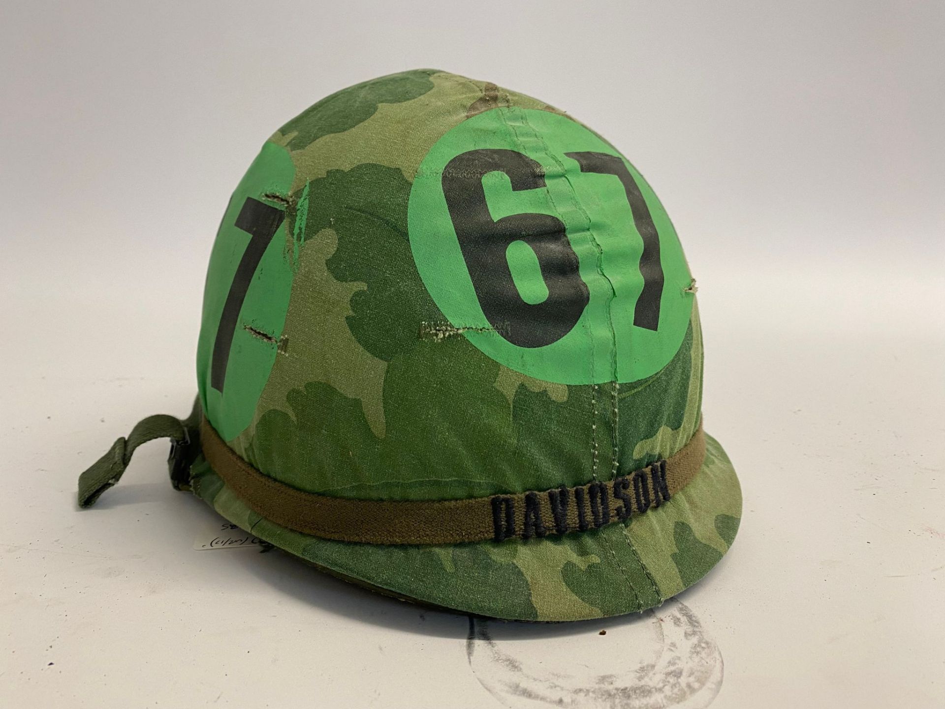 A US M1 airborne training helmet with embroidered band bearing the name Davidson. The cover with