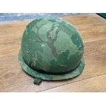 A US Vietnam era M1 helmet with liner and twill cover, chin strap marked with a P.