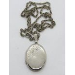 A hallmarked silver locket having part floral engraving to front, on white metal chain.