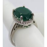 A silver and green stone solitaire cocktail ring, pierced gallery with halo design setting,