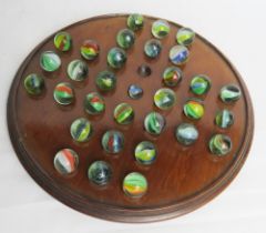 A mahogany solitaire board with hand blown glass marbles.
