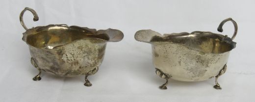 A pair of hallmarked silver sauce boats having pie crust edge and raised over three pad feet, 163.