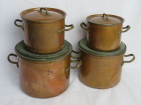 A set of four copper lidded pans.