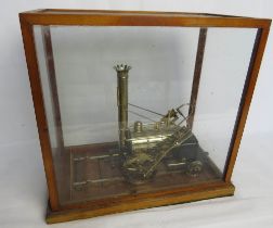 A glazed display box containg a brass steam engine.