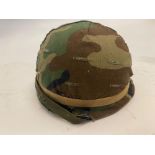 A US M1 helmet with woodland camo cover,