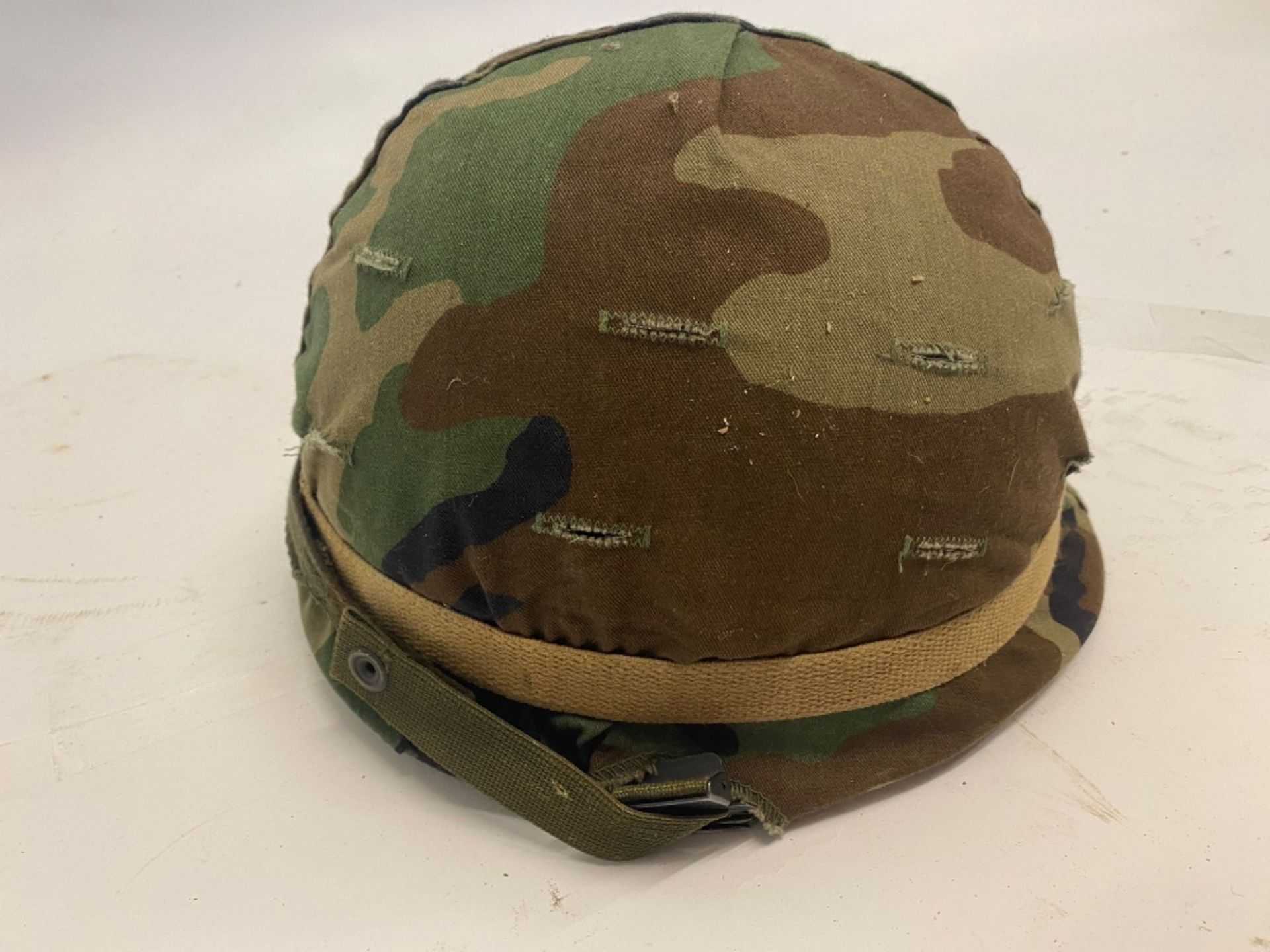 A US M1 helmet with woodland camo cover,