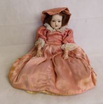 An antique Simon & Halbig doll in peach satin dress, having mark to back of head dated 1909,