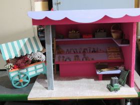A dolls house market stall with flower cart and shelves stocked with woodworking and maintenance
