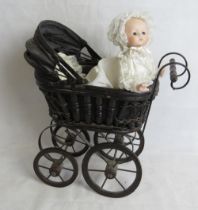 A porcelain headed baby doll having lullaby music box within, in wicker style pram.