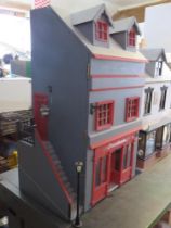 A dolls house furnished as a public house with home over, outside sign and lamp, barrel cart,