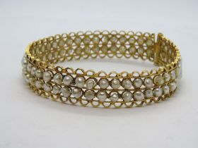 A yellow metal and cultured pearl set hinged bangle,