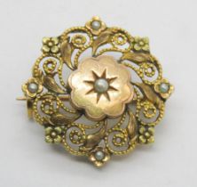 A yellow metal and seed pearl brooch of floral filigree desiggn, 2.5cm dia, 2.2g.