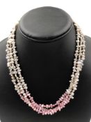 A THREE ROW STRAND OF CULTURED FRESHWATER PEARLS WITH AN OMBRE PINK AND GREY HUE. COMPLETE WITH A