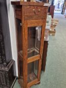 A GLAZED OAK GUN CABINET WITH A DRAWER ABOVE THE COMPARTMENT TO TAKE THREE GUNS. W 38.5 x D 35 x H