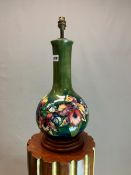 A MOORCROFT VASE AS A TABLE LAMP, THE SHADED GREEN GROUND BOTTLE SHAPE SLIP TRAILED WITH IRISES