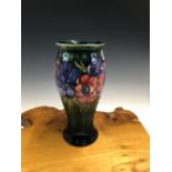 A WILLIAM MOORCROFT PEONY PATTERN BALUSTER VASE, THE FLOWER HEADS SLIP TRAILED ONTO A BLUE/GREEN