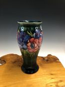 A WILLIAM MOORCROFT PEONY PATTERN BALUSTER VASE, THE FLOWER HEADS SLIP TRAILED ONTO A BLUE/GREEN
