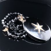 A MOURNING TYPE BLACK HARDSTONE LOCKET AND FACETED CHAIN. THE OVAL LOCKET WITH A SIX POINTED STAR