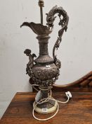 A PAIR OF SPELTER DOLPHIN HANDLED EWERS AS TABLE LAMPS, THE BALUSTER SHAPES SUPPORTING CUPIDS AND