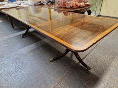 A SATIN WOOD CROSS BANDED MAHOGANY DINING TABLE SUPPORTED ON TWO COLUMNS, EACH WITH THREE LEGS AND