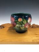 A WILLIAM MOORCROFT OVOID BOWL SLIP TRAILED WITH CLEMATIS FLOWERS ON A SHADED BLUE GROUND. H 13cms.