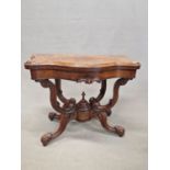 A VICTORIAN BURR WALNUT SWIVEL OPENING GAMES TABLE, THE SERPENTINE EDGED TOP ON FOUR BRACKETS JOINED