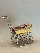 A VICTORIAN DOLLS FOUR WHEELED PRAM WITH A HOOD TO DRAW UP OVER THE BUTTON UPHOLSTERED BROWN